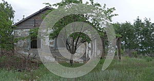 An old, abandoned house in the village, on a background of trees. Abandoned house near Donetsk. Destroyed houses and