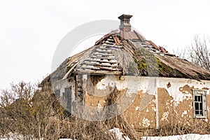 Old abandoned house. Weathered ruined building with broken straw roof. Aged rural home made ofrocks, stone and clay