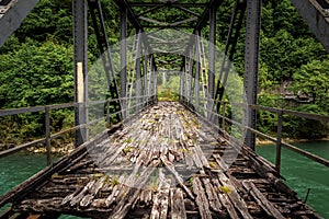 Old abandoned iron bridge spans over green river