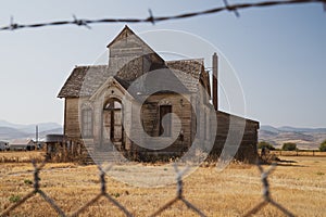 Old, abandoned LDS mormon church, framed by barbed wire, in Ovid, Idaho photo