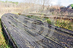 An old abandoned leaky wooden boat upside down lies on the Bank of river or lake