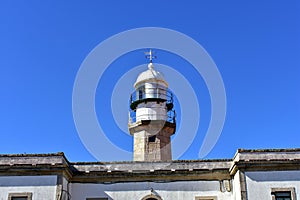 Old abandoned lighthouse with wind vane. Sunny day, blue sky. Galicia, Spain.