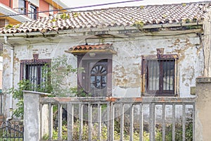 Old abandoned overgrown house behind a dilapidated fence