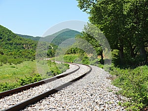 The old abandoned railway turns through a summer mountains