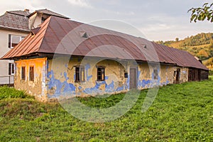 Starý opuštěný obytný dům postavený z pálených cihel, červená kovová střecha