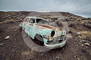 Old abandoned rusty car from 60`s in the desert.