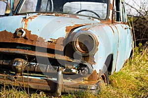 Old, abandoned rusty car wreck front and lamp.