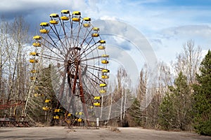 Old abandoned rusty metal radioactive yellow ferris wheel against dramatic sky in amusement park in ghost town Pripyat, Chernobyl