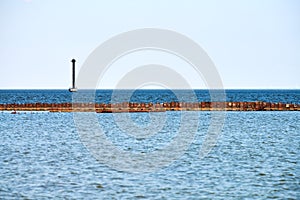 Old abandoned rusty sea pier for mooring boats and yachts on background of calm blue sea, horizon