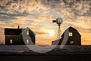 Old abandoned silhoetted house and barn with beautiful sunset