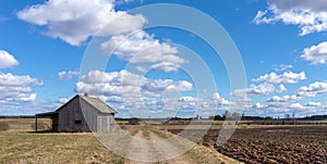 An old abandoned small wooden house in the field blue sky white clouds, barn or scary concept
