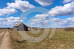 An old abandoned small wooden house in the field blue sky white clouds, barn or scary concept