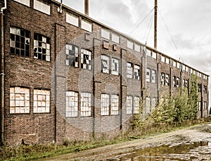 Old abandoned stone building with broken windows and a puddle outside