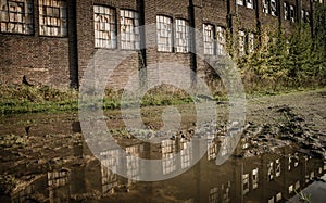 Old abandoned stone building with broken windows and a puddle outside