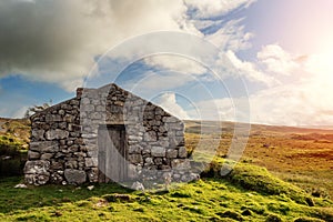 Old abandoned stone house without the roof. Sunset time. Rural Irish farm building. Dramatic sky. Old architecture example. Top