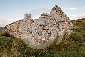 Old abandoned stone house without the roof. Sunset time. Rural Irish farm building. Dramatic sky. Old architecture example. Top