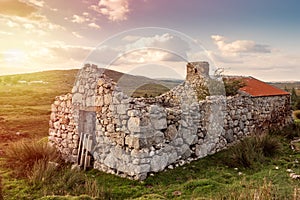 Old abandoned stone house without the roof. Sunset time. Rural Irish farm building. Dramatic sky. Old architecture example. Top