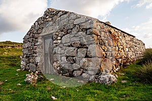 Old abandoned stone house without the roof. Sunset time. Rural Irish farm building. Dramatic sky. Old architecture example. Top