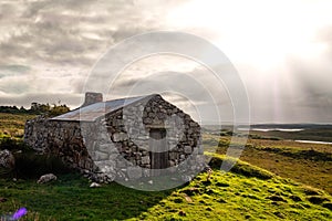 Old abandoned stone house without the roof. Sunset time. Rural Irish farm building. Dramatic sky. Old architecture example. Top