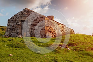 Old abandoned stone house without the roof. Sunset time. Rural Irish farm building. Dramatic sky. Old architecture example. Top