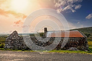 Old abandoned stone house without the roof. Sunset time. Rural Irish farm building. Dramatic sky. Old architecture example. Top