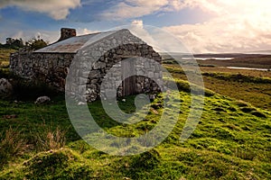 Old abandoned stone house without the roof. Sunset time. Rural Irish farm building. Dramatic sky. Old architecture example. Top