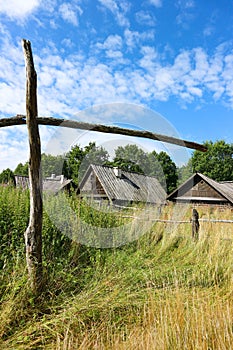Old abandoned village landscape with wooden houses and well crane under blue sky