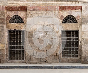 Old abandoned wall with two closed decorated wooden windows