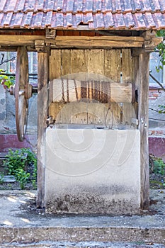 Old abandoned water well with rusty wheel in the village.