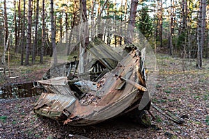 Old abandoned wooden fishing boat in the forest. Boat cemetery