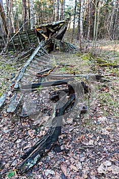 Old abandoned wooden fishing boat in the forest. Boat cemetery