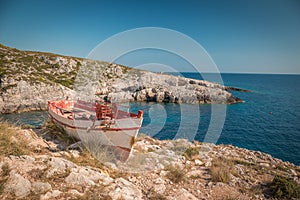 The old abandoned wooden fishing boat on a rocky cliff shore on a sunny day in greece. Zakynthos. Blue sea in the