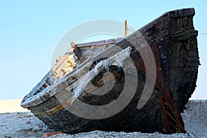 Old abandoned wooden fishing boat with rusted nails by the sea