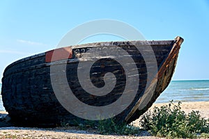 Old abandoned wooden fishing boat with rusted nails by the sea