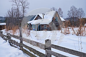 Old abandoned wooden house. The roof is covered with a thick layer of snow. Altai village Ust'-Lebed' in winter season