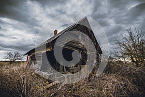 Old abandoned wooden house in a view of dark cloudy sky