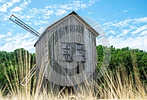 Old abandoned wooden mill and wheat summer field