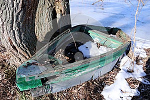 Old abandoned wooden rowboat near the frozen lake.