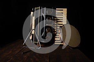 Old accordion, tambourine and triangle on rustic wooden surface with black background and Low key lighting, selective focus photo