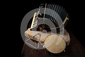 Old accordion, tambourine and triangle on rustic wooden surface with black background and Low key lighting, selective focus photo