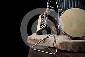 Old accordion, tambourine and triangle on rustic wooden surface with black background and Low key lighting, selective focus photo