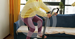 old active fit woman training with stationary bicycle at home.