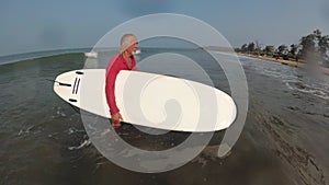 Old active healthy man surfing. Active life in retirement. Sports grandfather