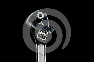 Old Adjustable Wrench and Nut on a Black Background