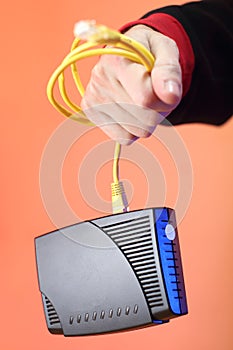 Old adsl modem hanging on a cable in a person`s hand