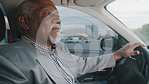 Old african american man driving car serious pensive elderly male leaves parking lot mature businessman looking closely