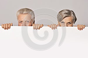 Old age couple holding blank banner