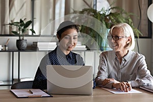 Old age female employee discuss project with young indian colleague