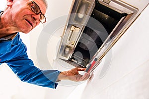 Old age handyman repair vent hood in the kitchen photo