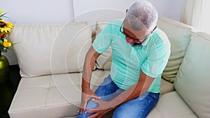 Old age, health problem. Older man suffering from leg pain at home